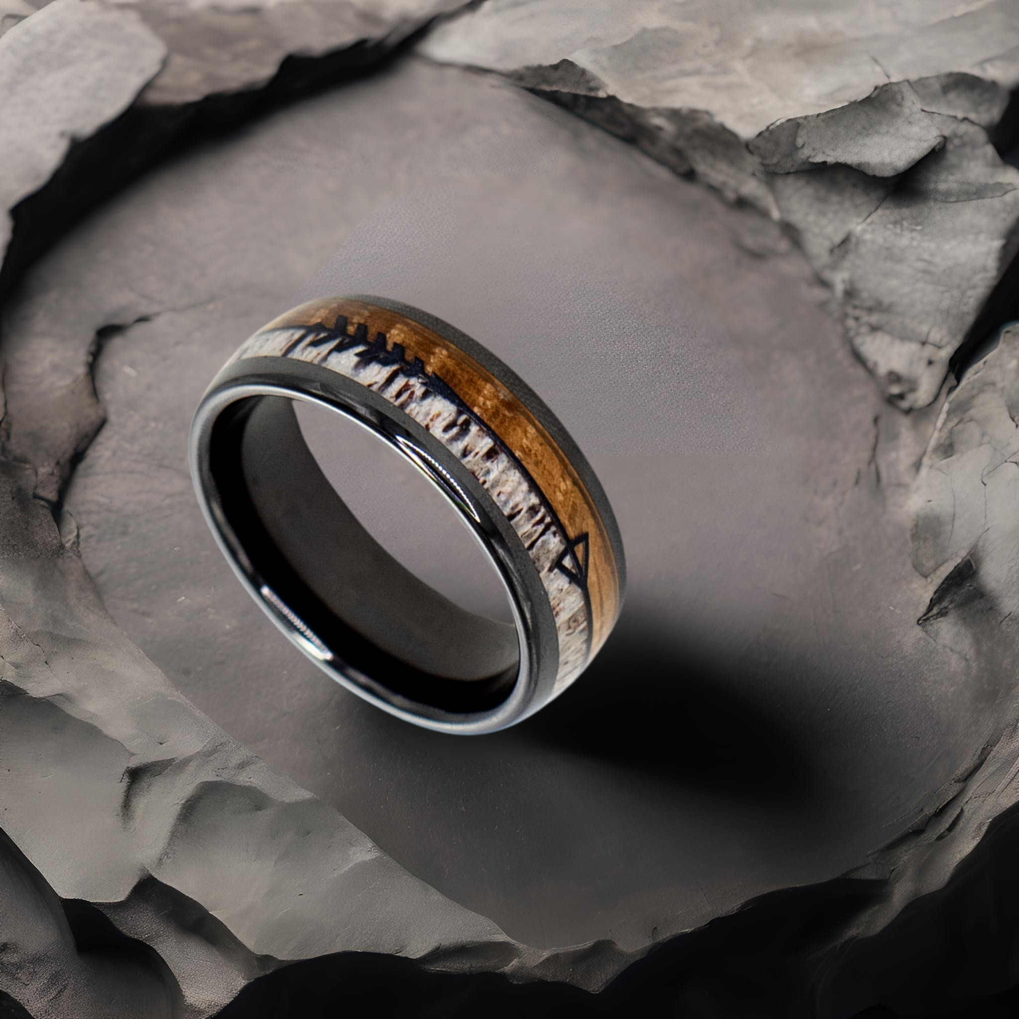 Eros ring – polished Black Ceramic featuring Whiskey Barrel Wood, Deer Antler and Black Arrow Foil part of the Hustler Collection. Lifestyle shot, placed on textured rock.