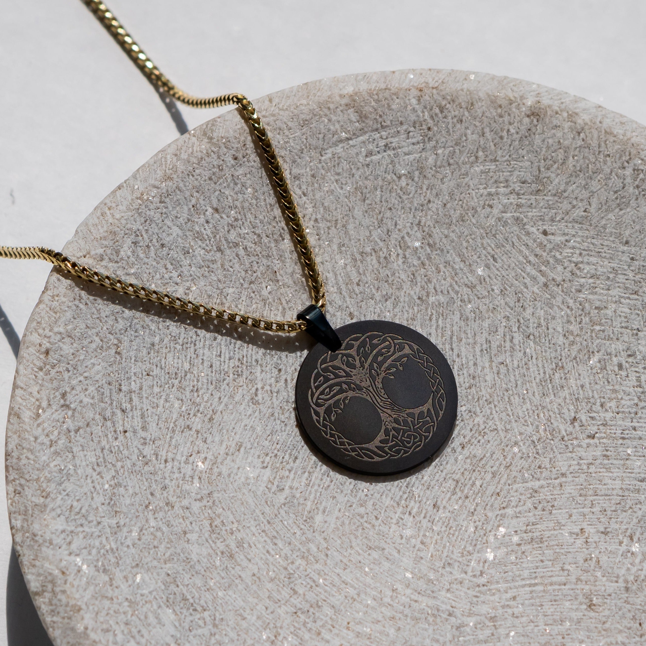 Ring shot #1 of man wearing our Elysium Men's Black Diamond Necklance & 26mm Custom Pendant with Gold Franco Chain resting on a marble surface | ElysiumBlack.com