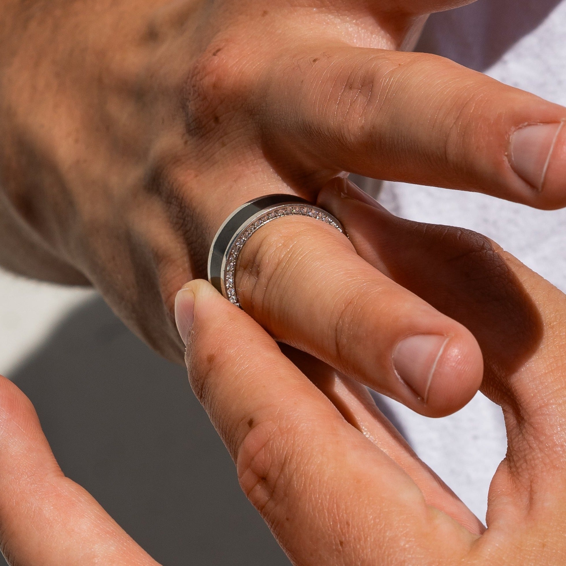 Ring shot #2 of our Elysium Zeus solid black diamond inlay ring with white diamond insets on a marble surface | Men’s Black Diamond Platinum Rings