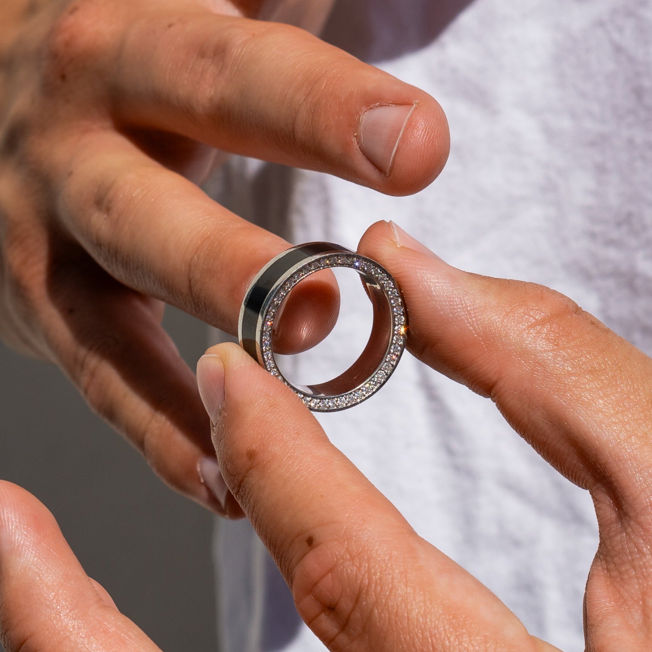 Lifestyle shot #1 of men's hands wearing our Elysium Zeus solid black diamond inlay ring with white diamond insets | Men’s Black Diamond Platinum Rings