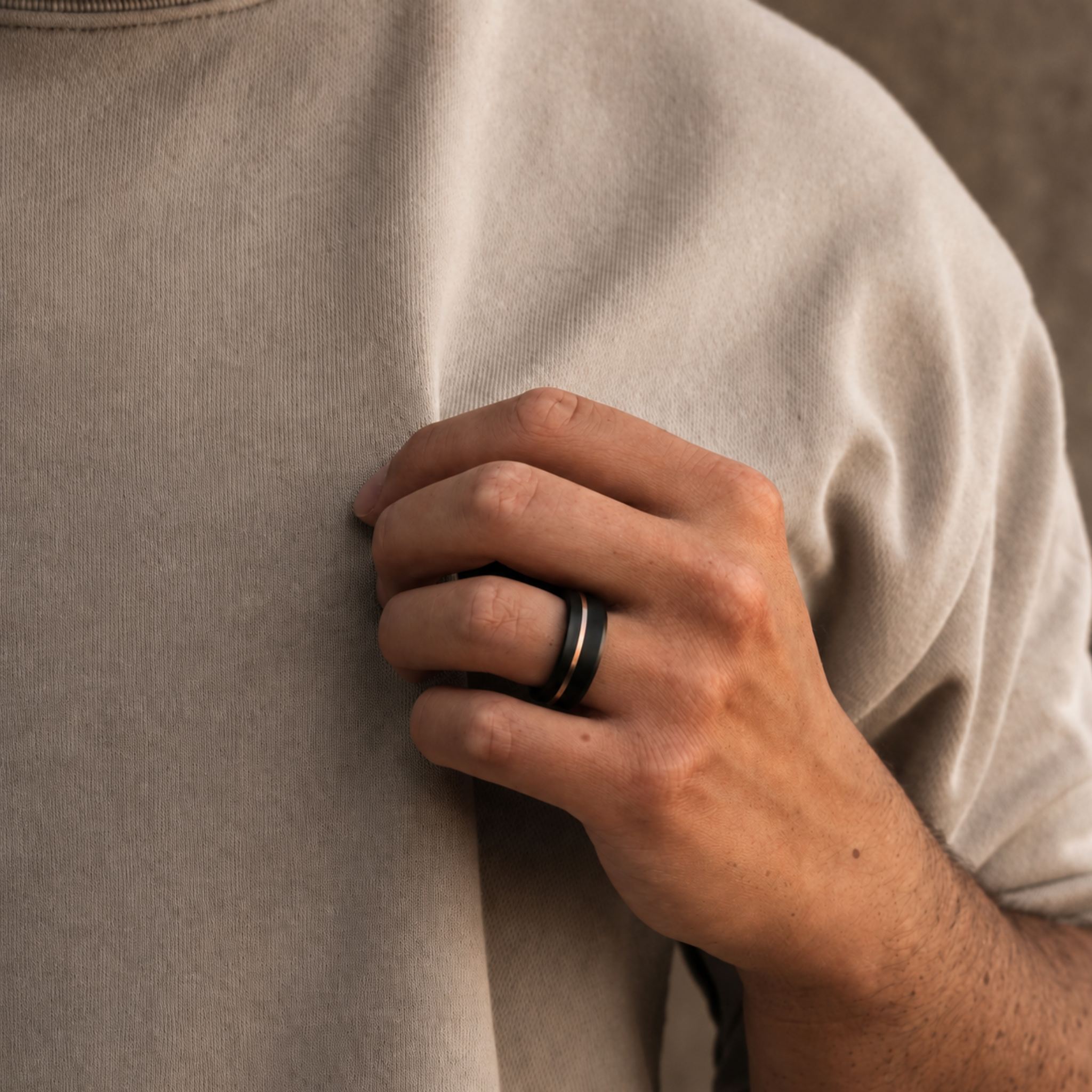 ARES solid black diamond ring with 10K rose gold offset inlay worn on hand showing the asymmetric inlay placement and beveled profile.