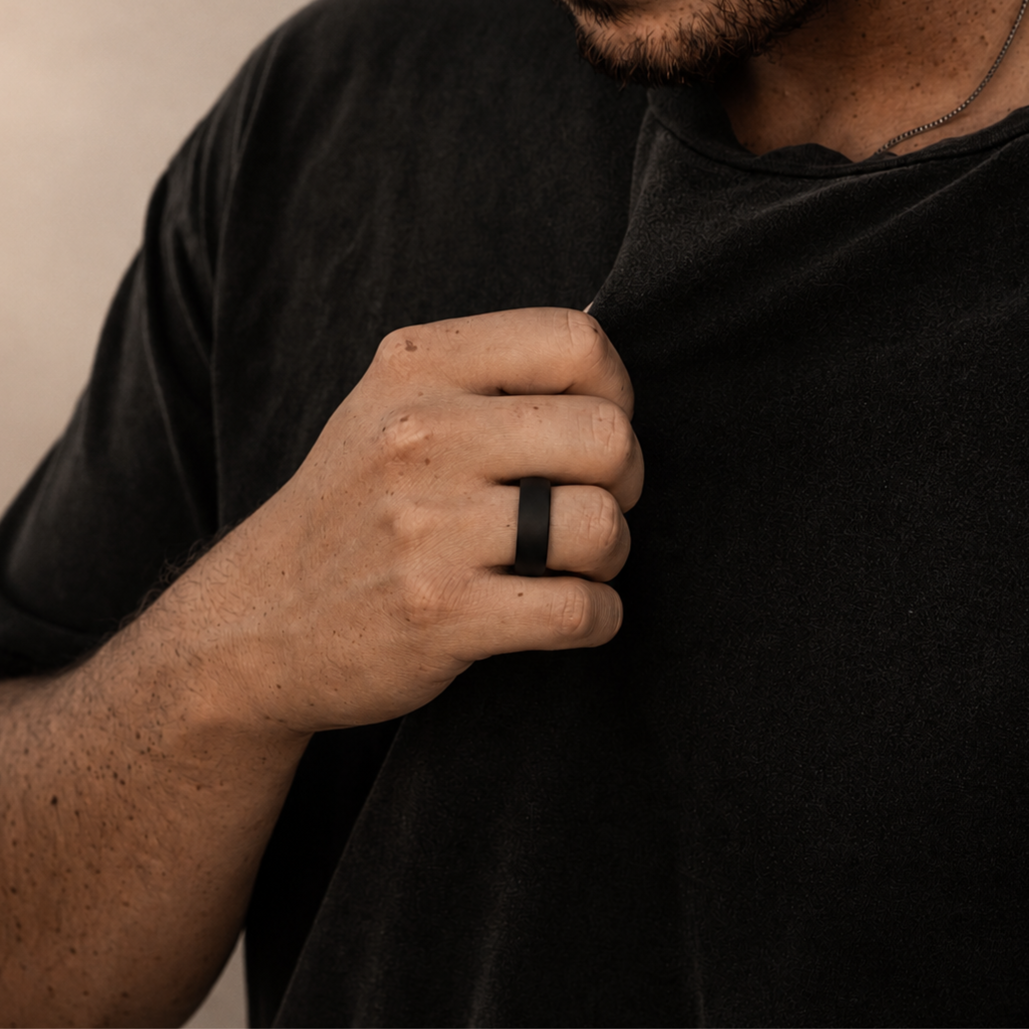 A close-up of a man wearing an 8mm NYX solid black diamond wedding band on his ring finger