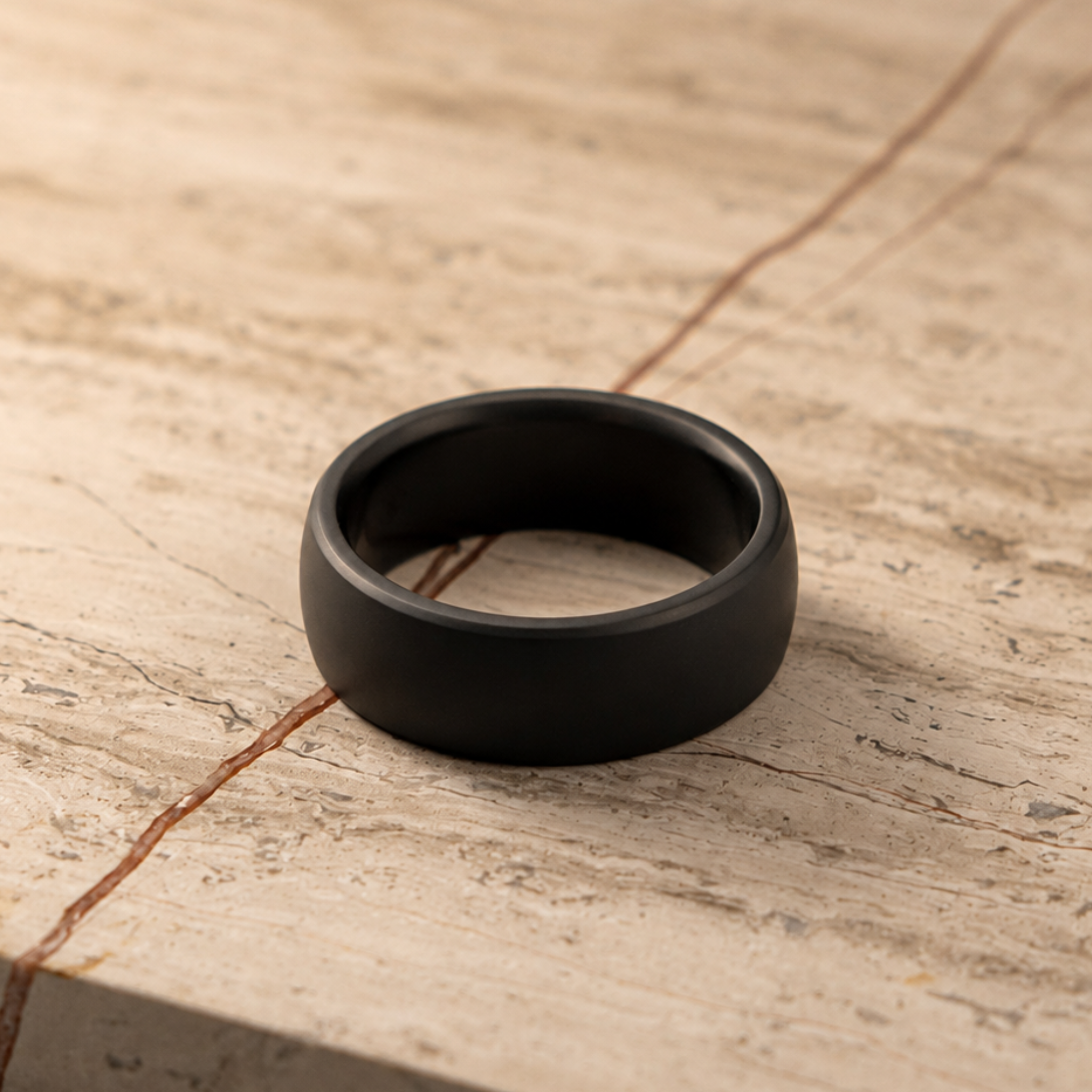 NYX solid black diamond wedding band band resting on a textured beige stone surface with natural cracks.